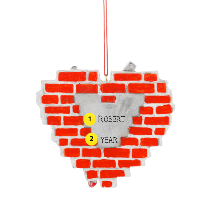 Back of Personalized Born to Fix ornament showing a silver personalization area with the example name Robert and year on a red brick wall background.