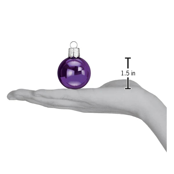 Size reference image for the Old World Christmas 1.5" Halloween ball ornament box sets, showing a purple mini ball ornament resting on an open hand with a 1.5 inch size marker beside it.