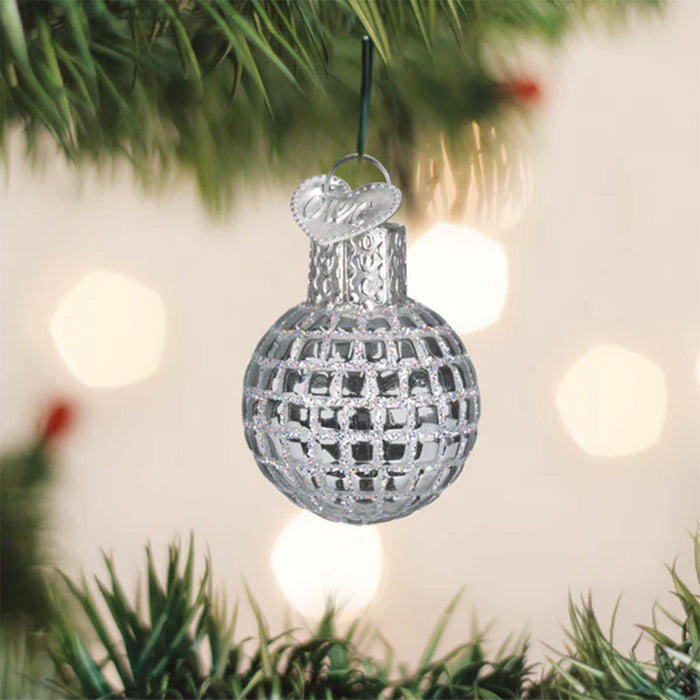 Decorative silver Disco Ball Christmas ornament hanging on a tree with blurred lights in the background
