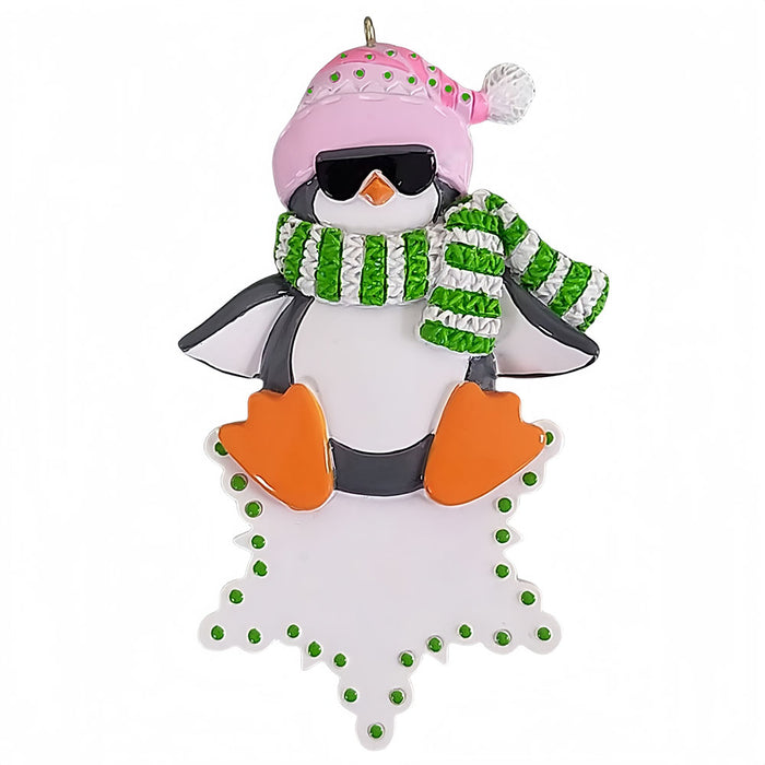 Decorative penguin ornament wearing a pink hat and green scarf on a white background