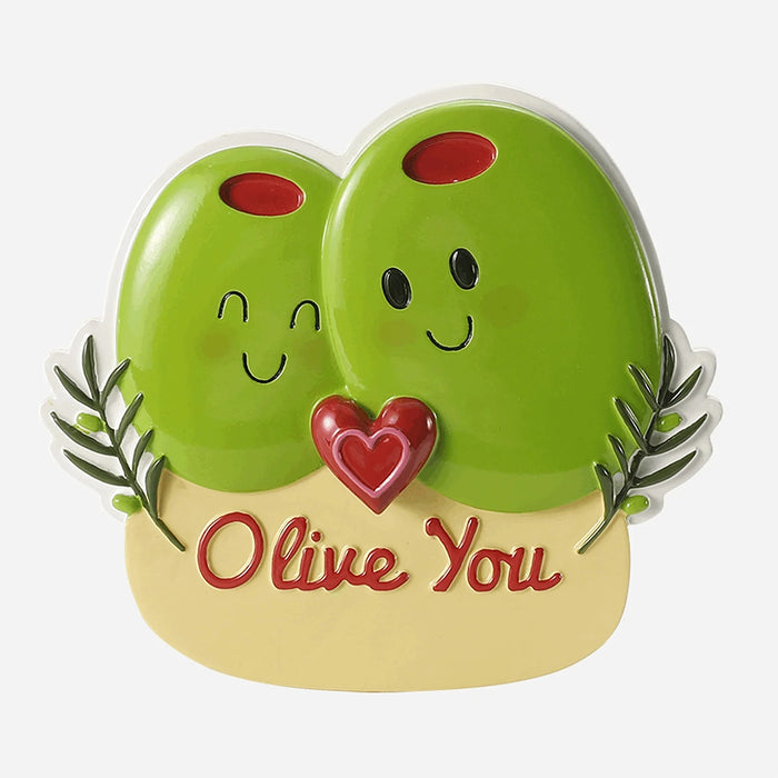 Two green olives with smiling faces and a heart, labeled 'Olive You' ornament, on a beige base with text.