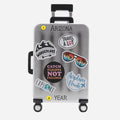 Silver suitcase ornament with travel-themed stickers on a white background can be personalized