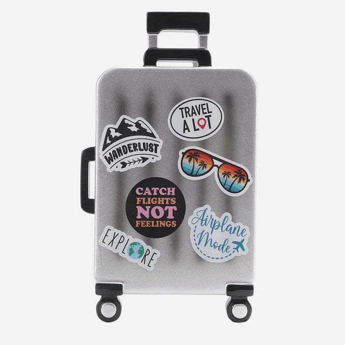 Silver suitcase ornament with travel-themed stickers on a white background can be personalized