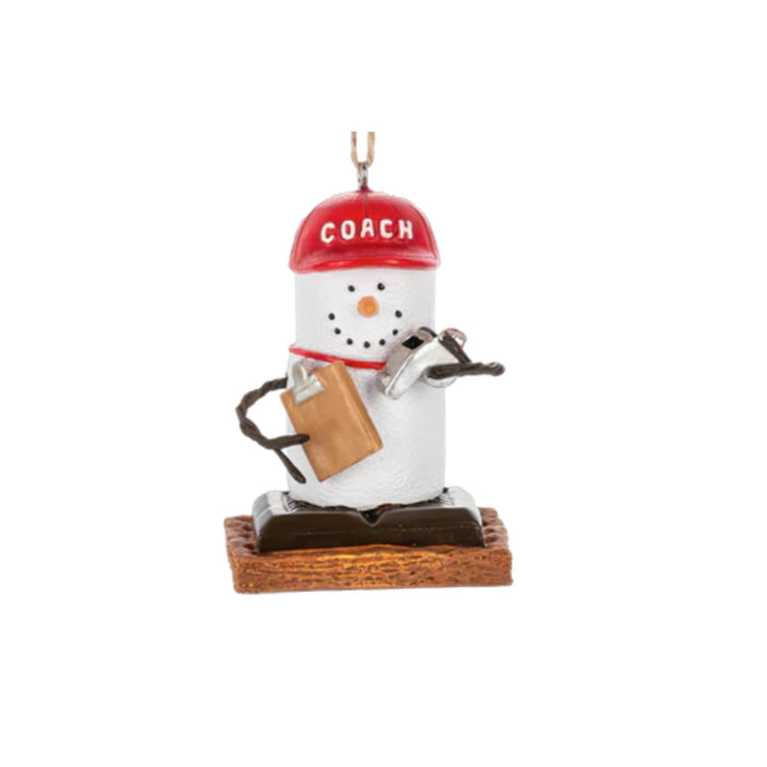 S’mores coach ornament featuring a marshmallow character wearing a red COACH hat, holding a clipboard and whistle, and standing on a graham cracker base.